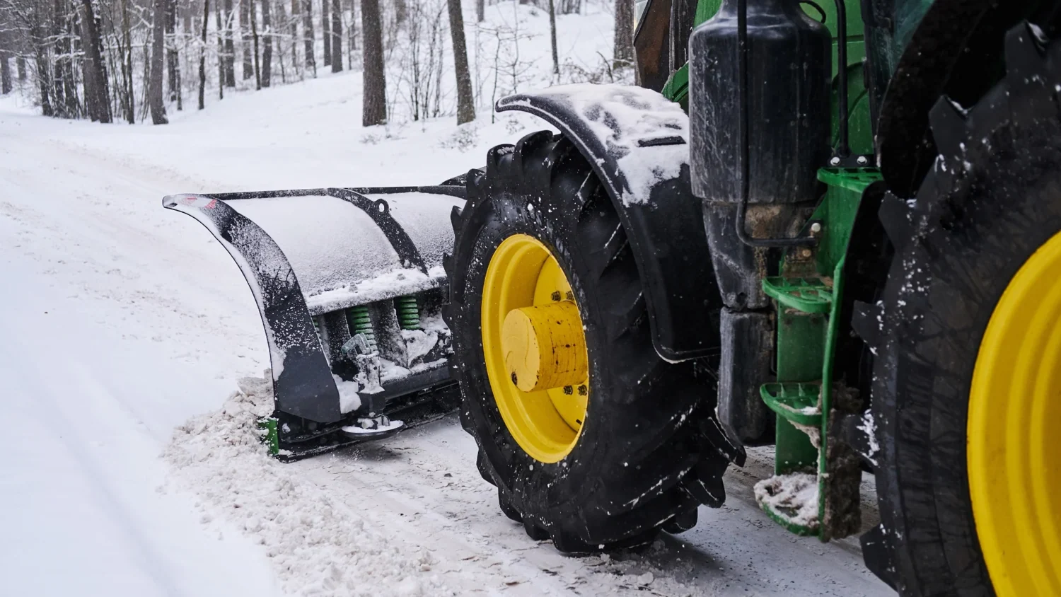 Tractor-mounted snow plow clearing winter snow
