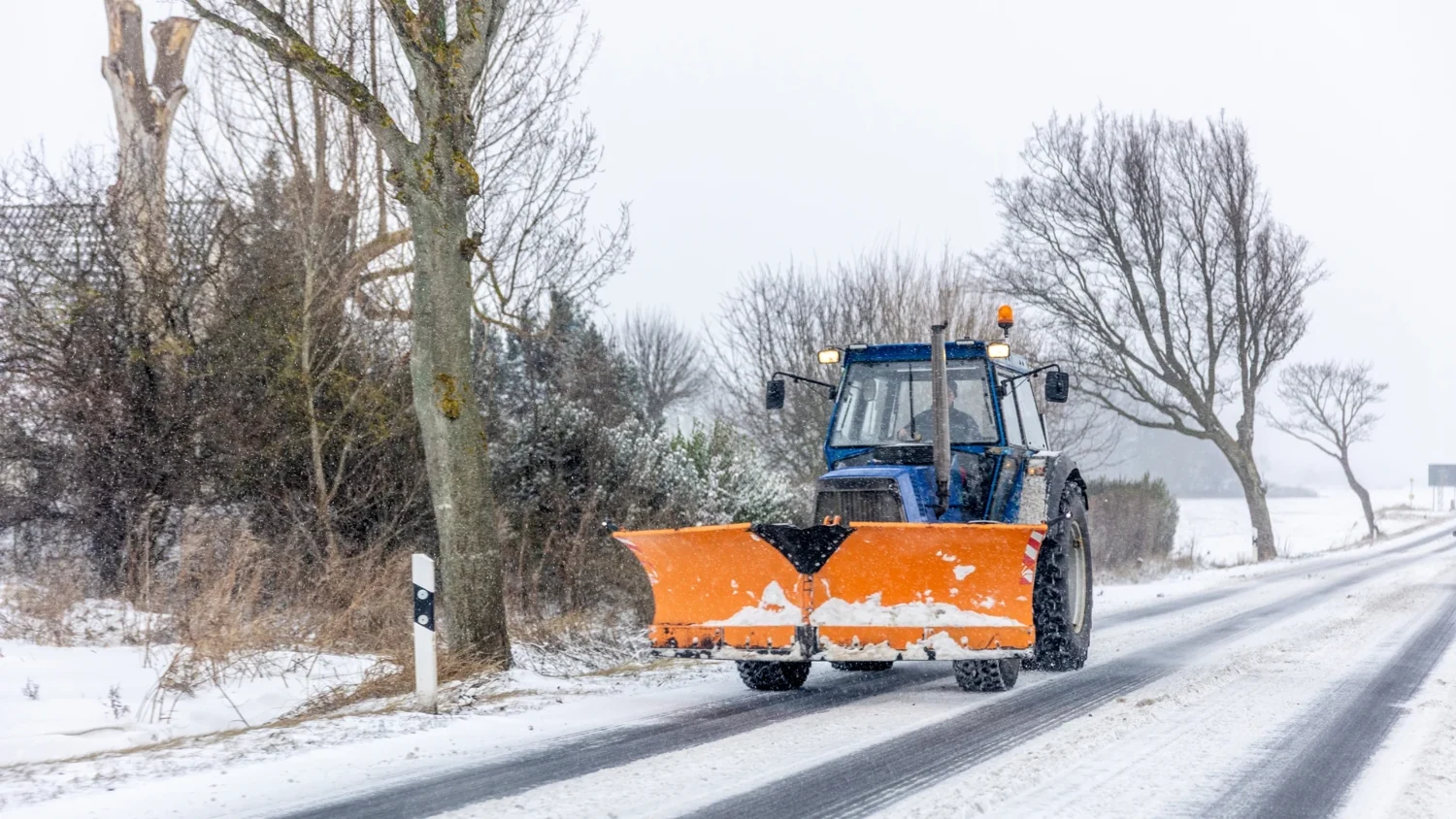 Tractor snow plow on a paved access route