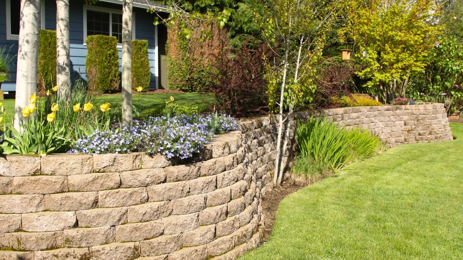 Curved block retaining wall beside a planted garden